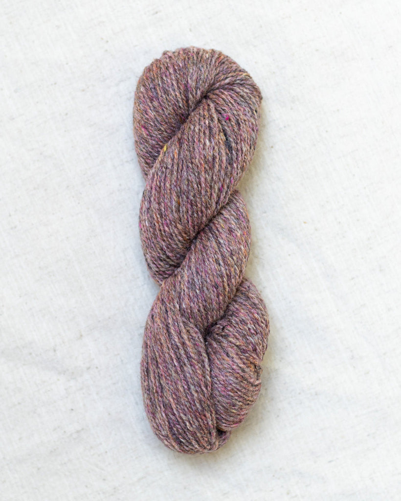 Single skein of heathered pinkish-purple yarn on a white background